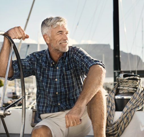 Senior man at the wheel of a sail boat