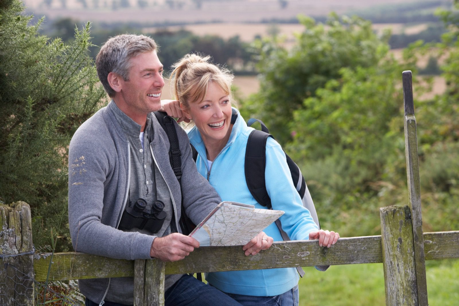 Middle-aged Couple, examining map, while hiking in the woods