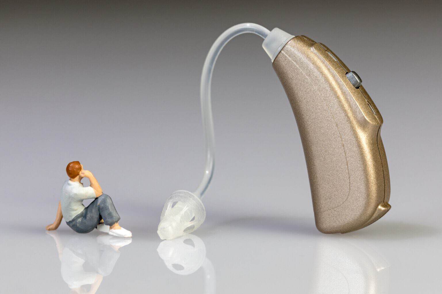 Miniature figurine of man looking at a hearing aid